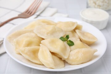 Plate of delicious dumplings (varenyky) with cottage cheese on white table, closeup