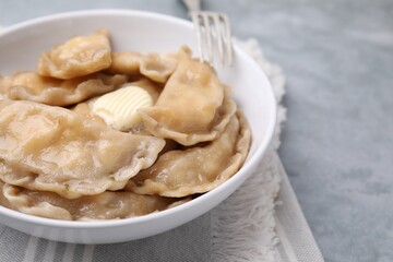 Delicious dumplings (varenyky) with cottage cheese and butter served on light grey table, closeup
