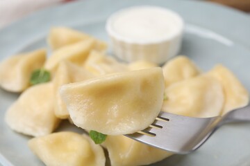 Delicious dumpling (varenyk) with cottage cheese on fork over plate, closeup