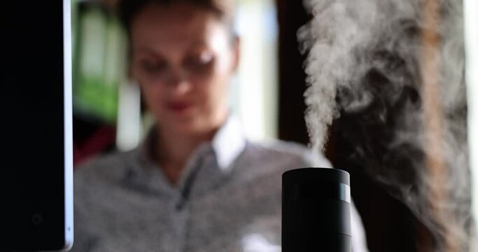 Closeup of running humidifier on desktop in office. Black essential oil diffuser with vapor flow