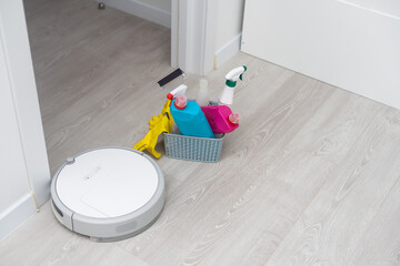 Picture of an automatic intelligent robotic vacuum cleaner and colorful cleaning product on the...