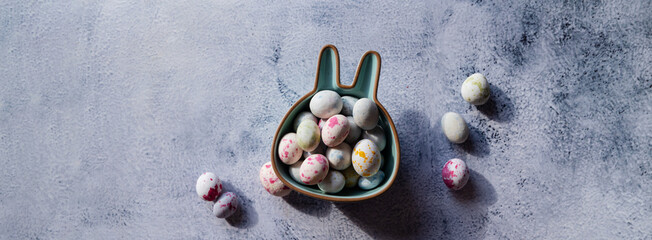 Colored chocolate Easter eggs in a bowl in the form of a bunny. Easter background with copy space