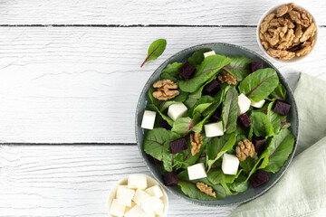 Beetroot salad with feta cheese, chard and walnuts on a white background. Top view. Copy space....