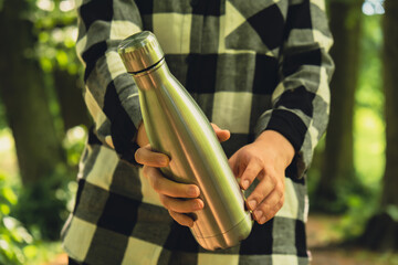Close-up of Unrecognizable female hand holding Water bottle. Reusable steel thermo water bottle in...