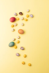 Colored eggs of different sizes on a yellow background. Symbol of the Easter holiday. Easter background. Top view