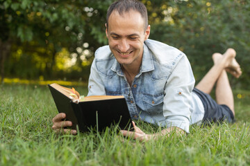 Naklejka na ściany i meble a man reads the Bible on the grass at a park