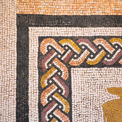 Ancient Italian Roman mosaic floor with geometric shapes composed of small colored stone tiles