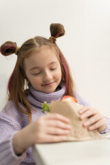 Cute little girl with ponytails biting a sandwich. Adorable white kid eating lunch meal in a fast food restaurant