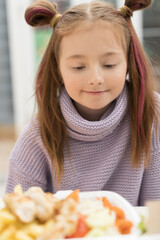 Hungry little girl looking at food on the table. Portrait of adorable white kid ready to take a bite of fast food for lunch in a cafe