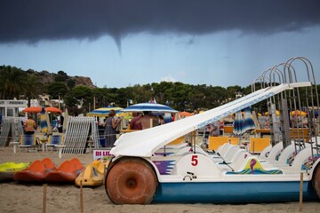evocative image of pedal boats on the beach waiting to be used in the sea
with a whirlwind...