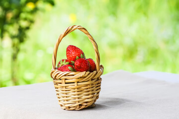 Fresh ripe strawberries in wicker basket outdoors.