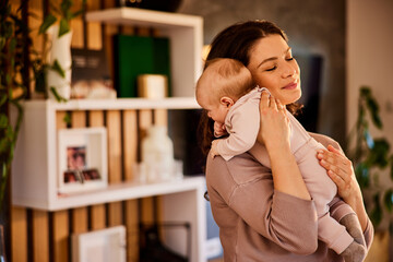 A caring mother holding her little baby in her arms after eating at home.