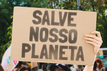 A person holding a brown save our planet cardboard poster. Carbon Footprint. Climate Change....