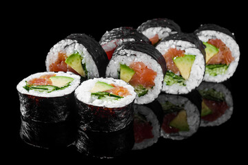 futomaki sushi roll with cucumber salmon avocado on a black mirror background