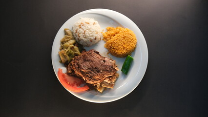 Beef breast ribs served with rice and appetizers on a serving plate