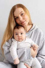 Mom and baby play on the bed. Mother and son, happy family, beautiful blonde girl and cute baby at home.