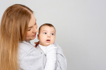 Mom and baby play on the bed. Mother and son, happy family, beautiful blonde girl and cute baby at home.