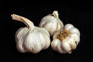 Three heads of garlic on a black background