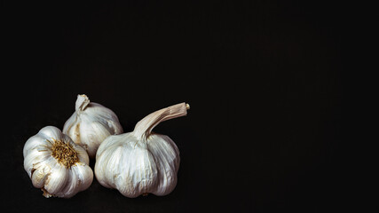 Three heads of garlic on a black background
