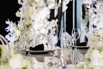Wedding set up, dinner table reception in banquet area on party. Flower composition in center of table. Banquet decoration in hall restaurant. Luxury silver decor. Setting. Side view.