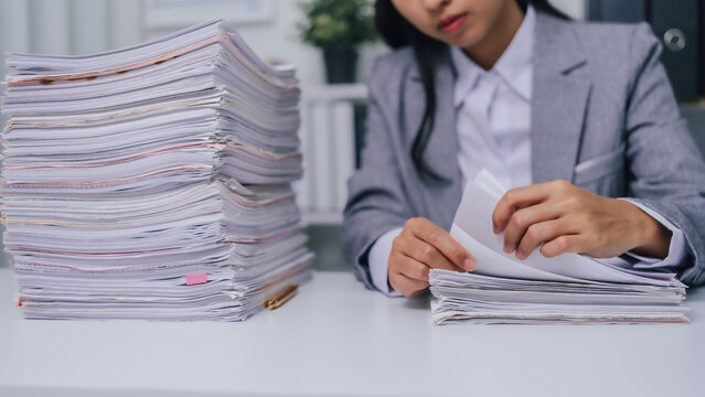 Find some document paper, Young confident asian business woman office worker people working with stack of papers, unfinished documents of bookkeeping.