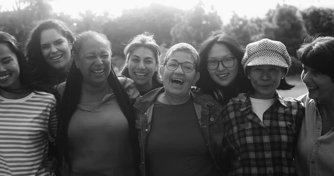 Group of multigenerational women hugging each other outdoor - Multiracial female friends with different ages having fun together at city park 