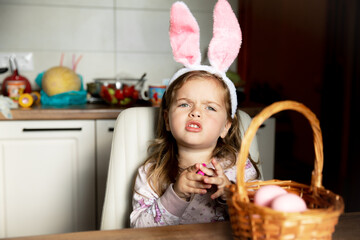 Little beautiful girl with easter bunny ears on with her basket of easter eggsHappy Easter holiday.
