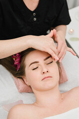 Fototapeta na wymiar Cosmetologist making rejuvenating face procedures client in spa salon. Aesthetic cosmetology, face care. Facial treatment, skincare concept. Girl getting face, head massage treatment. Relaxing massage