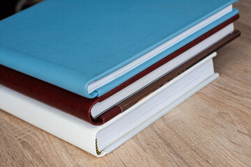 Three stylish photo books with leather covers, white, burgundy and blue, of different thicknesses,...