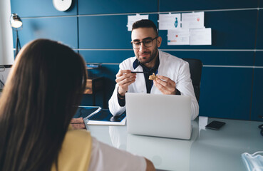 Positive young physician pointing at vertebra model during appointment