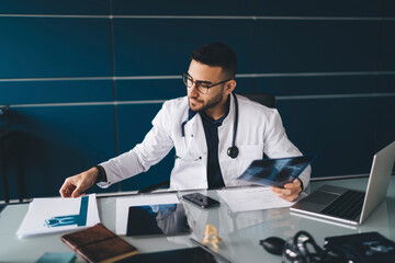 Focused doctor working with documents and x ray images in office