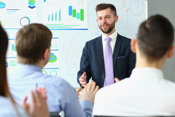 Male business coach speaker in suit makes presentation on white board. Male speaker advising on...
