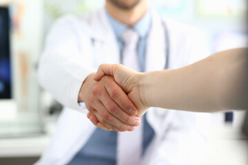Obraz na płótnie Canvas Doctor shaking hands with patient in clinic and thanking handshake for excellent treatment. Trust partnership and health insurance concept