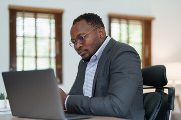 middle aged man American African using computer laptop with planning working on financial document, tax, exchange, accounting and Financial advisor