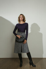 Serie of studio photos of young female model wearing viscose fitted shirt and patterned woolen midi...