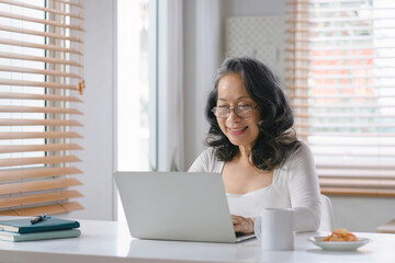 A senior businesswoman entrepreneur is working remotely from her home office, captured in a portrait.