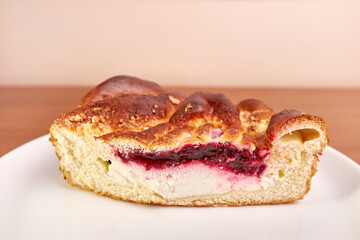 Delicious pie with cheese and cherry jam on a white plate.