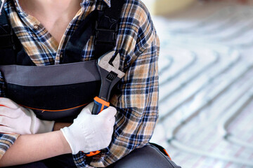 The master, dressed in overalls and a shirt, holding a wrench in his hand. Maintenance. construction concept