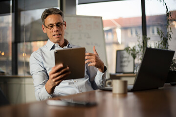 Portrait of businessman in office. Man using digital tablet. Businessman having video call..