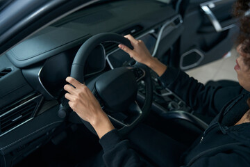 Curly-haired woman sits behind wheel in interior of modern car