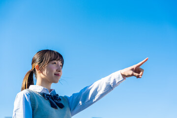 制服で上を指差す女子高生