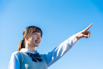 制服で上を指差す女子高生