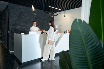 Young man offering amenities brochure to female