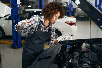 Multiracial young repairwoman checking oil level in car