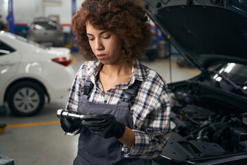 Fototapeta na wymiar Multiracial auto repair shop employee in work clothes standing near car