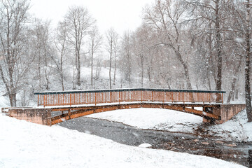 Fototapeta premium Small bridge over a river in winter snowy park