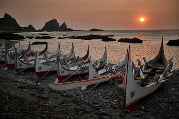 A row of Tao canoes resting on a beach during sunrise, photographed in Lanyu (Orchid Island).    © David Lin