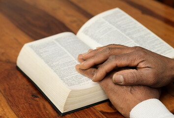 Naklejka premium praying to God with hand on the bible on lack background stock photo