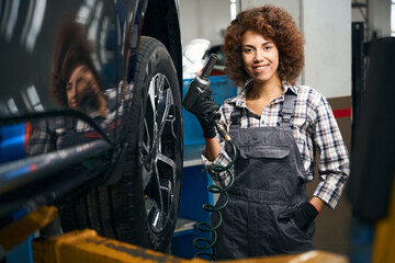 Cute woman repairman holds a pneumatic screwdriver in her hands