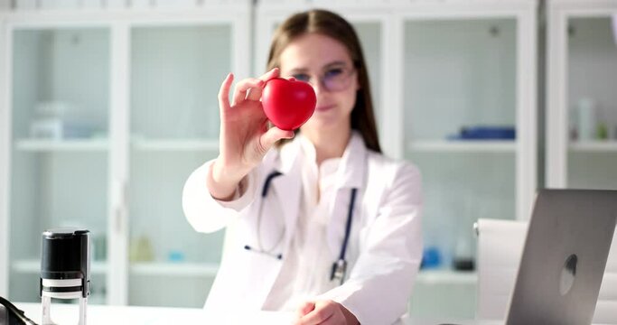 Therapist cardiologist holds red heart in hand in clinic. Cardiology and heart health